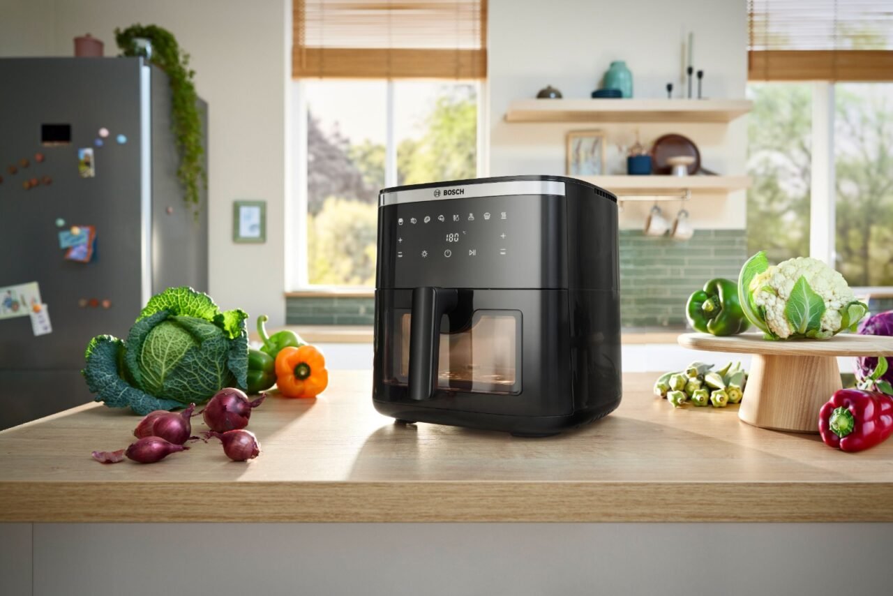 Bosch CrispMaxx airfryer on a kitchen counter, surrounded by fresh vegetables, showcasing modern appliance convenience for healthy cooking