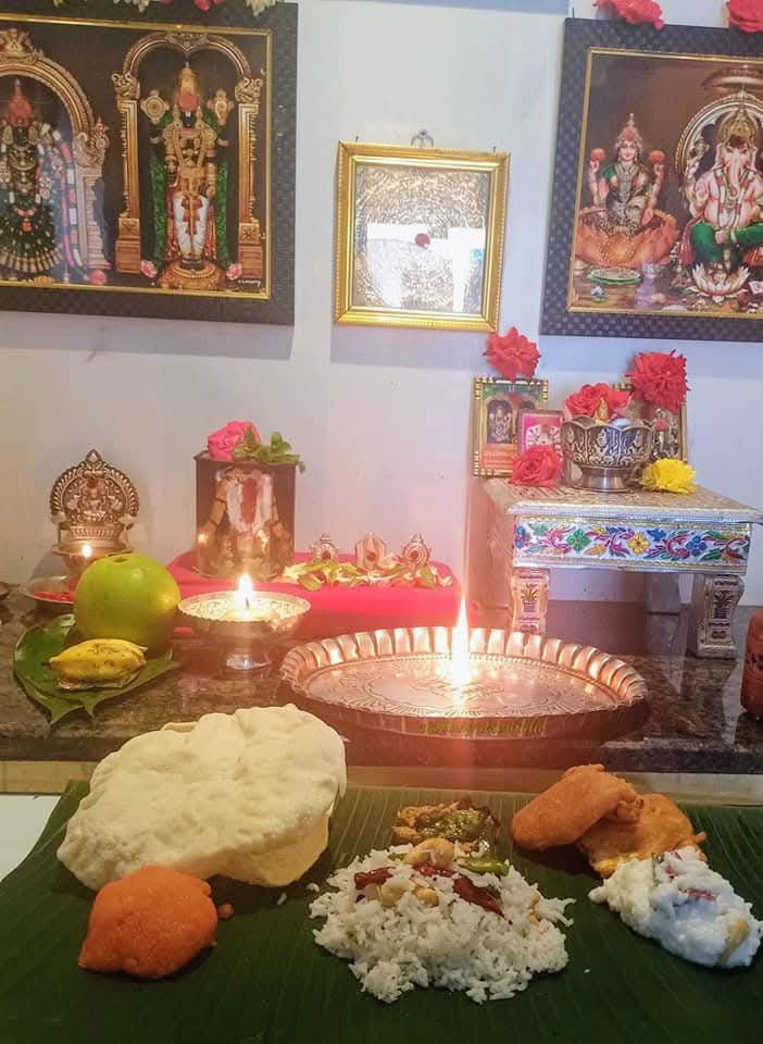 Setup for Puratasi, featuring a banana leaf meal with rice, vadai, appalam, and sweet pongal, alongside lit diyas and framed deities on a festive altar.