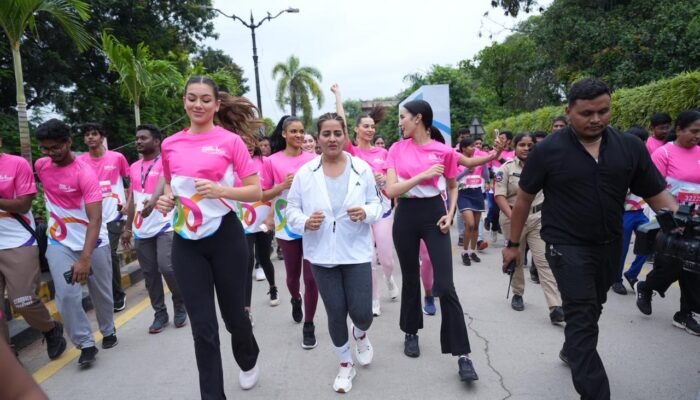 A group of female participants, wearing bright pink shirts, running down a road in the Pink power run 2025 event
