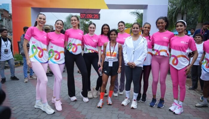 A group of female runners and event participants, many wearing pink, pose for a photo at the Pink power run 2025 finish line, with a race clock visible in the background.