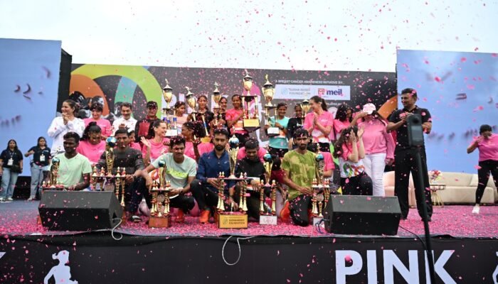 Award winners and organizers celebrating on stage with numerous trophies, surrounded by pink confetti, at the Pink power run 2025 awards ceremony.